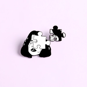 Detailed macro of two-piece puzzle enamel brooch featuring a stylized female face portrait