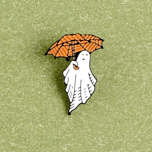 Close-up of Halloween enamel pin featuring a cute ghost holding a pumpkin umbrella