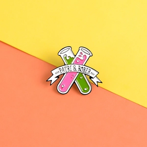 Macro shot of chemical test tube enamel pin with pink and green liquid on split background