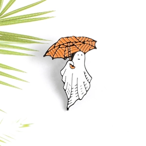 Macro shot of a cute white ghost enamel pin holding an orange umbrella for Halloween