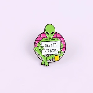 Detailed enamel finish on alien zinc alloy brooch with Need To Get Home sign