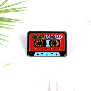 Détail macro d'une broche cassette émaillée rétro avec lettrage Hope World et fini métallique