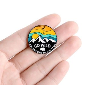 Outdoor adventure enamel pin featuring snow mountains sunset and a black bear silhouette