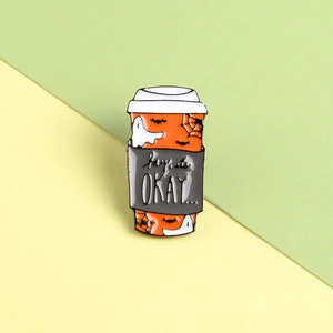 Macro view of orange Halloween coffee cup enamel pin with ghost and spider web details