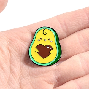 Broche en émail avocat mignon avec cœur, présentée dans la main pour la taille