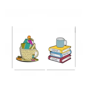 Dettaglio delle spille in smalto a forma di libro e tazza con scritte Drink Read Love