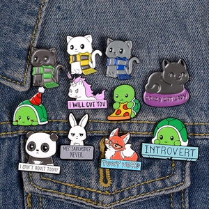 Colorful enamel animal pins featuring cat, panda, and fox on blue denim fabric background