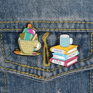 Spille creative in smalto con libri e tazza di caffè su una tasca di giacca in denim