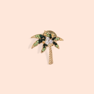 Golden coconut tree brooch with sparkling green rhinestones on a soft pink background