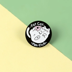Detail of a round enamel Fat Cat Fan Club pin with cute white cat on black metal base