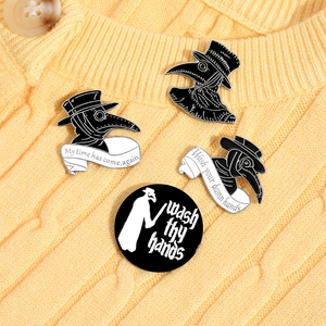 Set of four black and white plague doctor enamel pins on a yellow knit sweater background