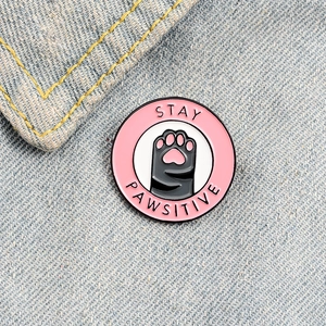 Broche créative en émail avec patte de chat grise et inscription Stay Pawsitive