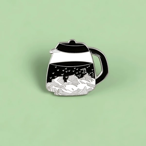 Close-up of coffee pot enamel pin featuring a creative starry night and mountain landscape
