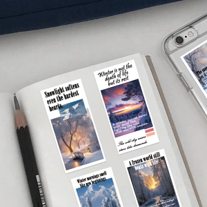 Close-up of artistic winter scenery stickers with poetic text on a notebook page