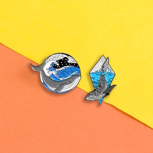 Macro view of cartoon whale enamel pins with intricate ocean waves and star details