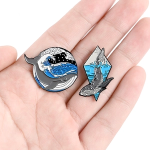 Ocean wave enamel pins set featuring cartoon whale designs on a palm for size scale