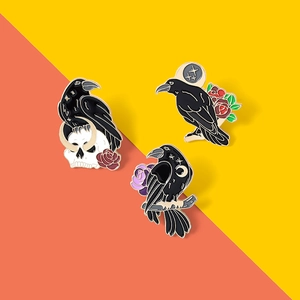 Detailed view of black crow enamel pins featuring skull, moon and rose mystic motifs
