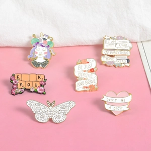 Detail of colorful enamel letter pins with inspiring quotes on a soft pink background