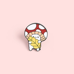 Détail d'un pin's émaillé en forme de champignon mignon avec chapeau rouge sur fond rose