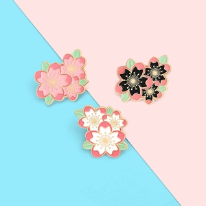 Vue détaillée de trois épingles en émail sakura avec bords dorés et feuilles vertes