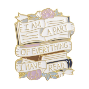 Detail of enamel book brooch featuring text I am a part of everything I have read