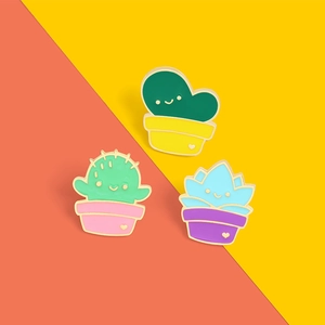 Detail of three cute cartoon potted plant enamel pins with smiley faces on vibrant background