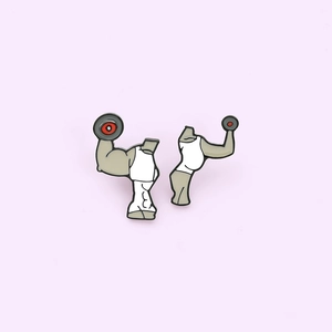 Detail of creative fitness enamel pins showing muscular arms and dumbbell pieces