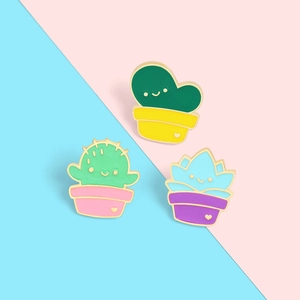 Detailed close-up of three cute cartoon potted plant enamel pins with smiley faces