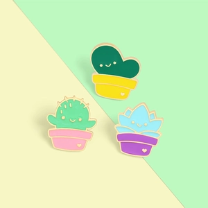 Detailed view of three cute succulent enamel pins with smiling faces in pastel colors