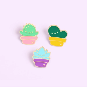 Detailed close-up of three cute enamel cactus succulent lapel pins in colorful pots