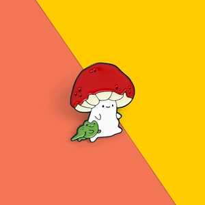 Gros plan d'un pin's émaillé mignon en forme de fantôme champignon avec une grenouille