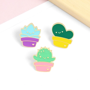 Three cute cartoon succulent cactus enamel pins with colorful pots on wooden background