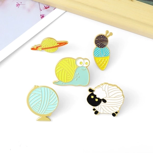 Close-up of five creative cartoon yarn ball enamel pins featuring sheep and planet shapes