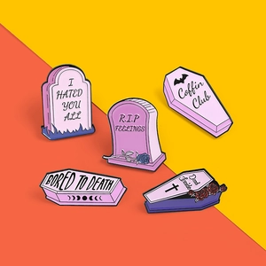 Detail of pink and purple gothic enamel pins with tombstone and coffin motifs