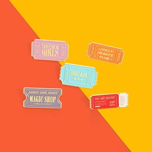 Detail view of five colorful enamel ticket pins including Magic Shop and Lovesick Girls designs