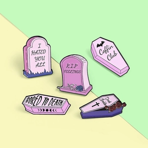 Macro view of five pink gothic enamel pins featuring coffins, tombstones, and roses