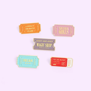 Five creative colorful enamel pins set inspired by movie tickets and VIP passes on lilac back