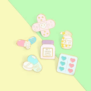 Macro view of medical enamel pin set featuring cartoon pill bottle and heart bandages