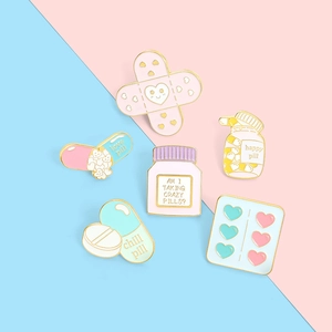 Detail of 6 cute enamel pins set with pill, capsule, and band-aid shapes in macaron colors