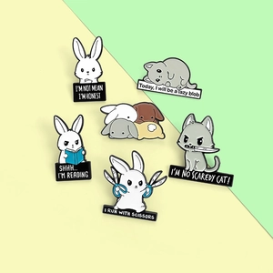 Detail showing cartoon enamel animal pins with funny quotes on a pastel background