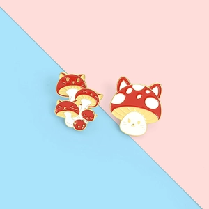 Detailed macro view of two cute enamel mushroom and cat badges with glossy gold plating
