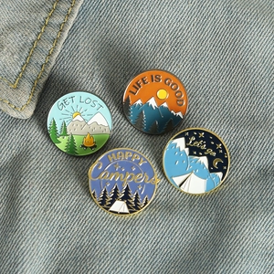 Outdoor camping enamel pin set with mountain, campfire, and tent designs on denim