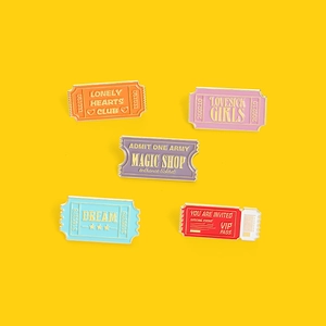Colorful set of five K-Pop themed enamel pins with golden borders on yellow background