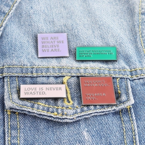 Enamel slogan pins set with motivational quotes on blue denim jacket pocket