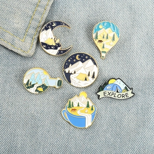 Set of 6 outdoor camping enamel pins with moon and mountain designs on denim fabric