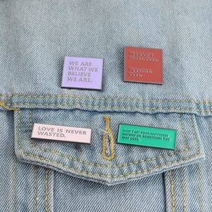 Enamel badge set with inspirational quotes on denim jacket pocket, minimalist design