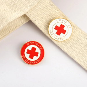 Detailed close-up of COVID-19 Vaccinated enamel pins with red cross on fabric