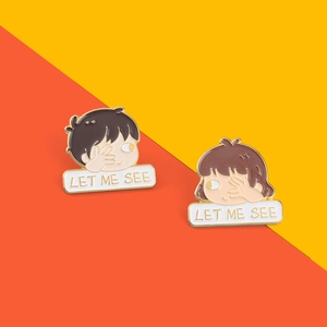 Close-up of alloy enamel pins featuring cartoon characters with LET ME SEE text label