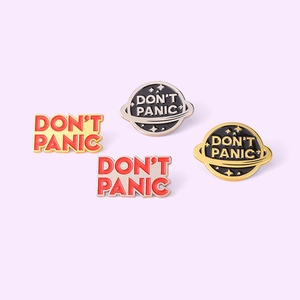 Set of four Don't Panic enamel pins featuring round planet and text designs on metal