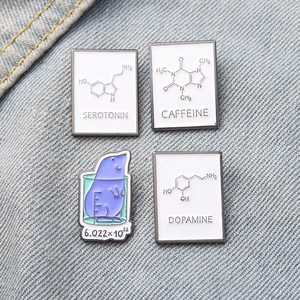 Detailed view of science enamel pins with chemical structures on denim fabric background